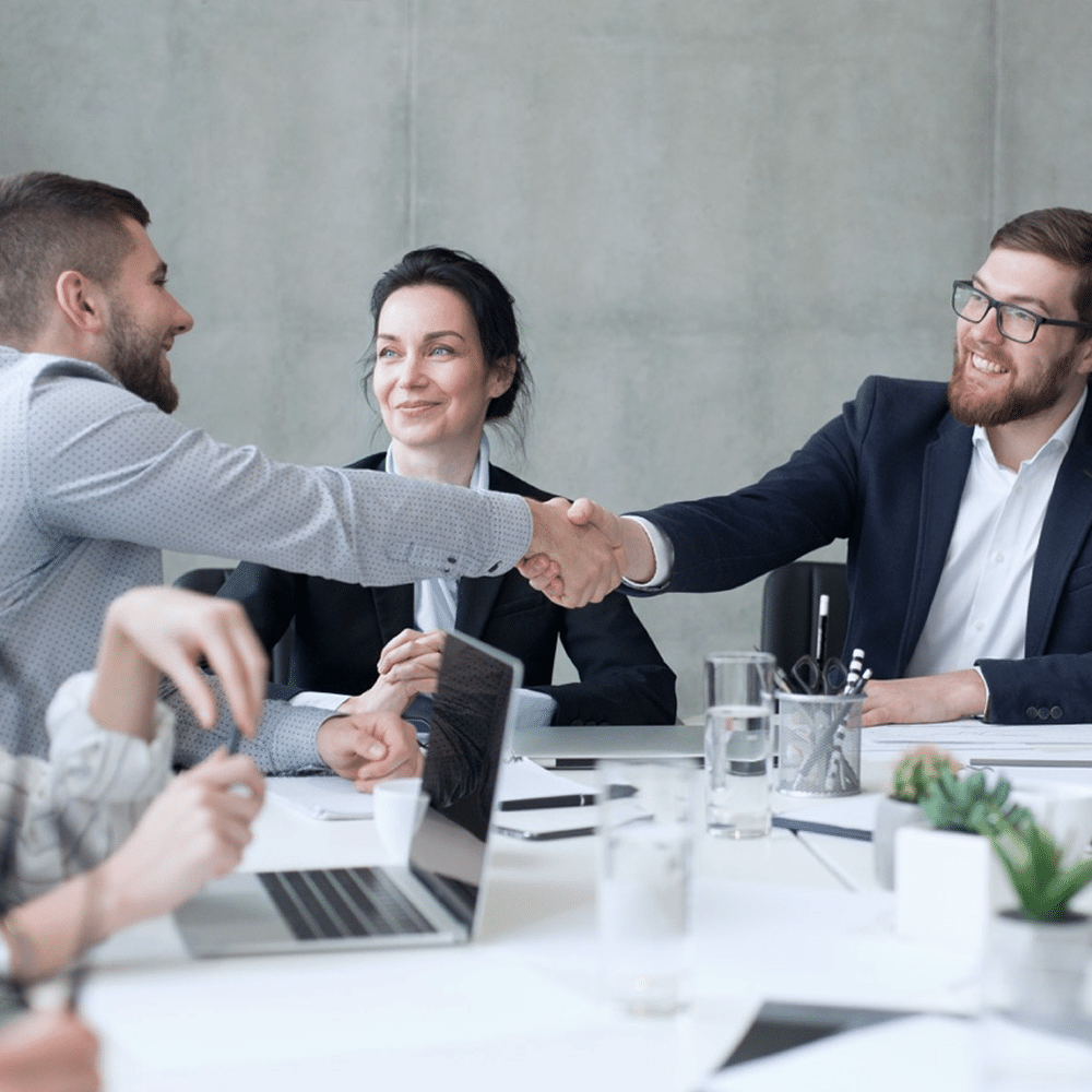 Two people shaking hands during a meeting.
