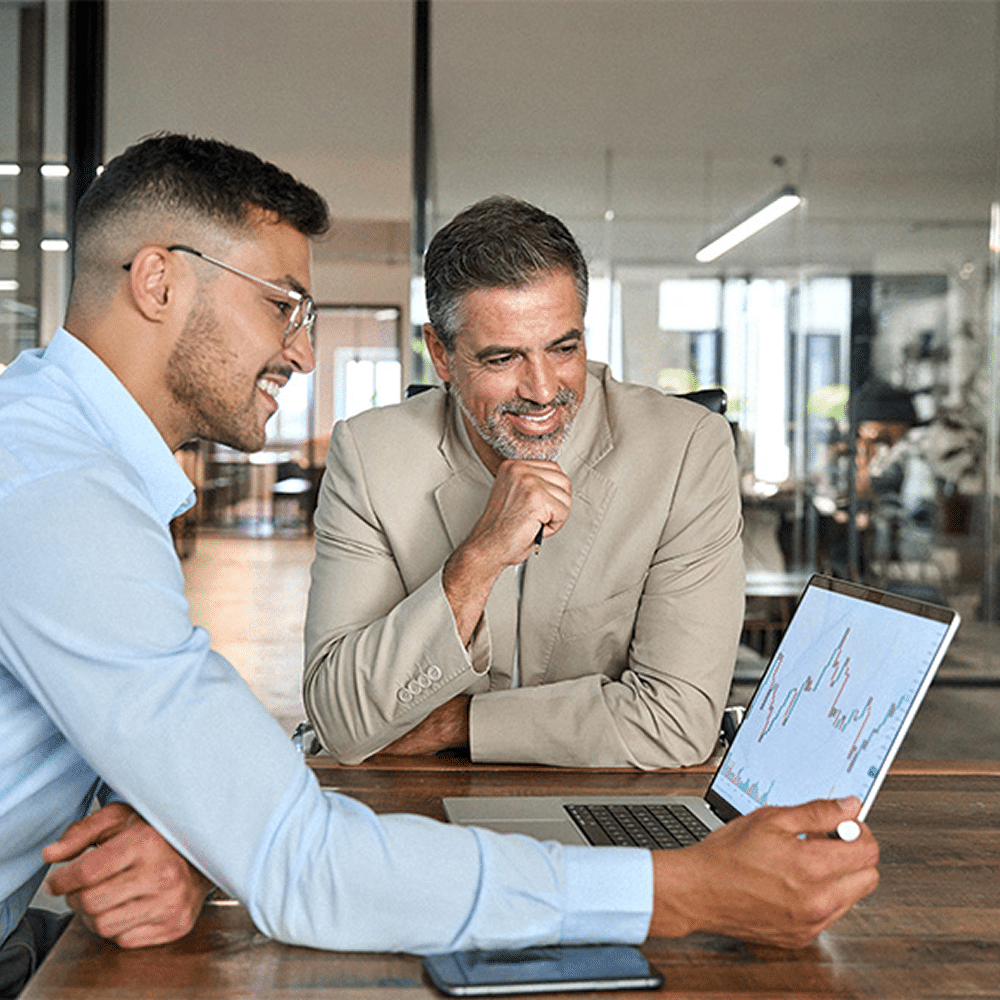 Two coworkers reviewing charts on a tablet in an office.