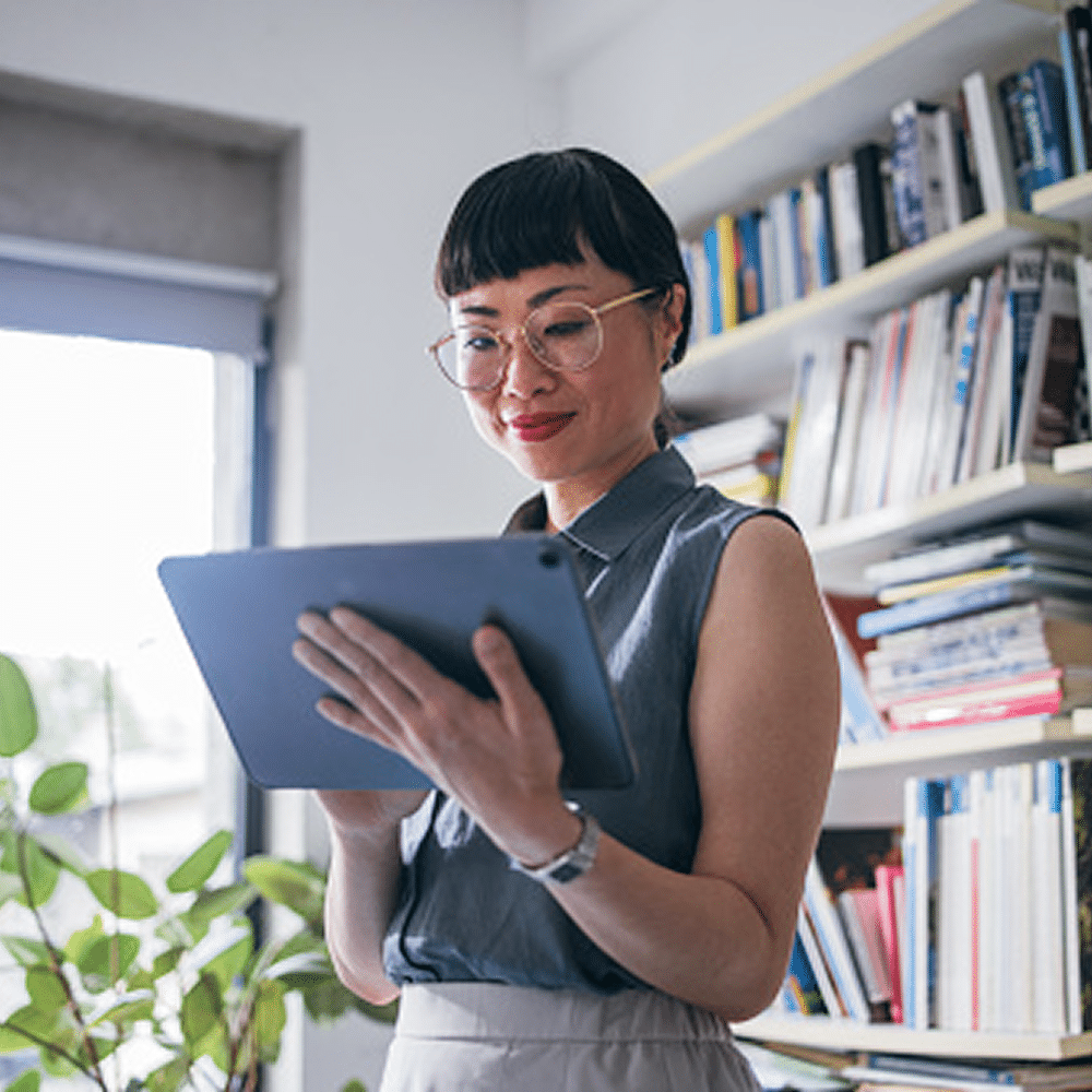 Person reading on a tablet in front of bookshelves